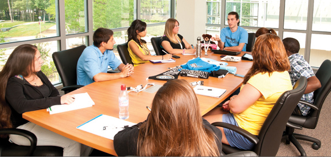 cilvēki sēž ap galdu